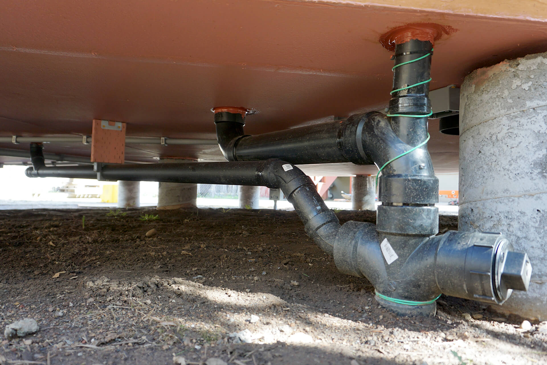 Underfloor waste pipes and conduit as viewed from the crawlspace.