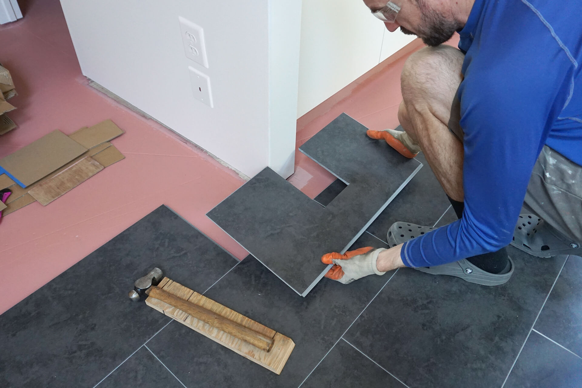 Installing luxury vinyl tile around the kitchenette wall.